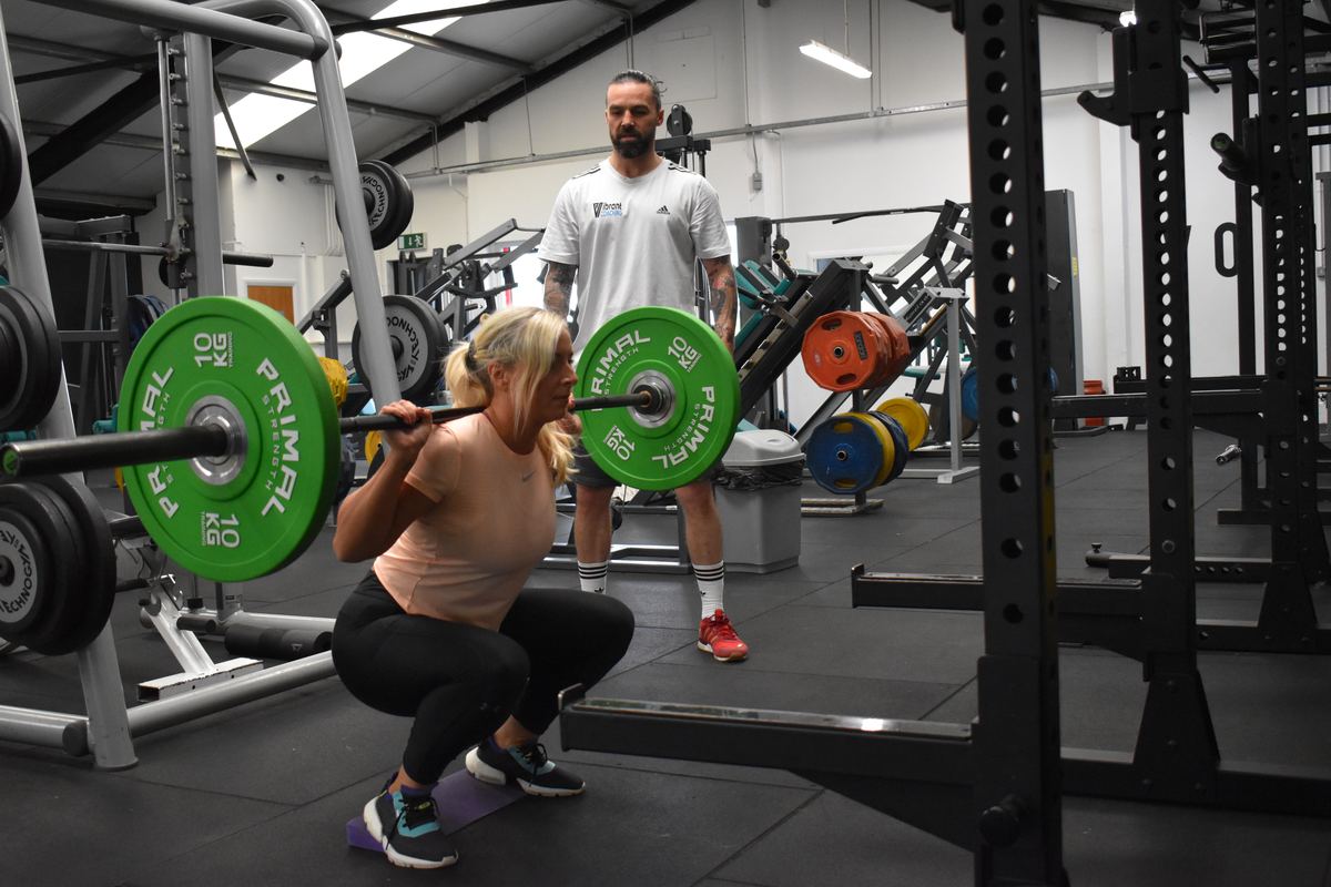 Ian Wilson coaching a client through a barbell back squat